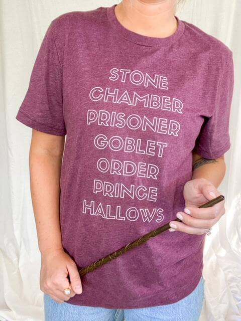 Heather Maroon Tee Shirt that reads: Stone, Chamber, Prisoner, Goblet, Order, Prince, Hallows in white block lettering.