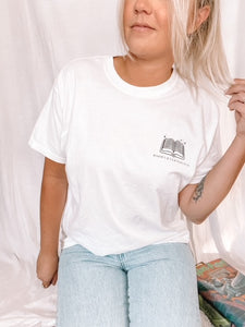 woman wearing white tee shirt with black logo that reads "Books and Cleverness" with art of an open book above it.