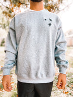Load image into Gallery viewer, man wearing Charcoal Gray sweatshirt with 3 black embroidered stars on the left chest.
